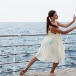Young beautiful ballerina dancing and posing outside, sea background.